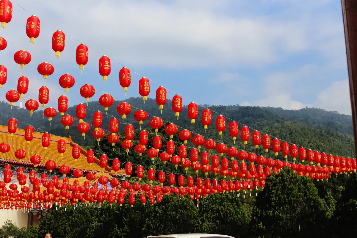 Colorful red Chinese lanterns hanging for a vibrant festival outdoors under a clear blue sky.