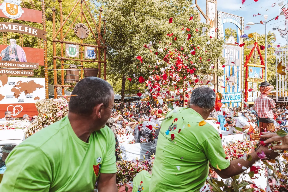 A vibrant outdoor parade with people throwing flower petals in Barcelos.