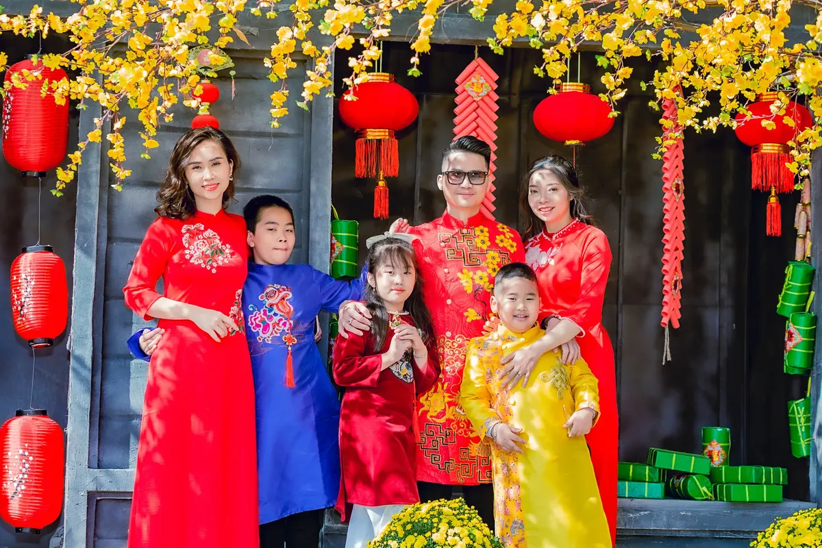 Happy Asian family in traditional attire celebrating Lunar New Year with red lanterns.