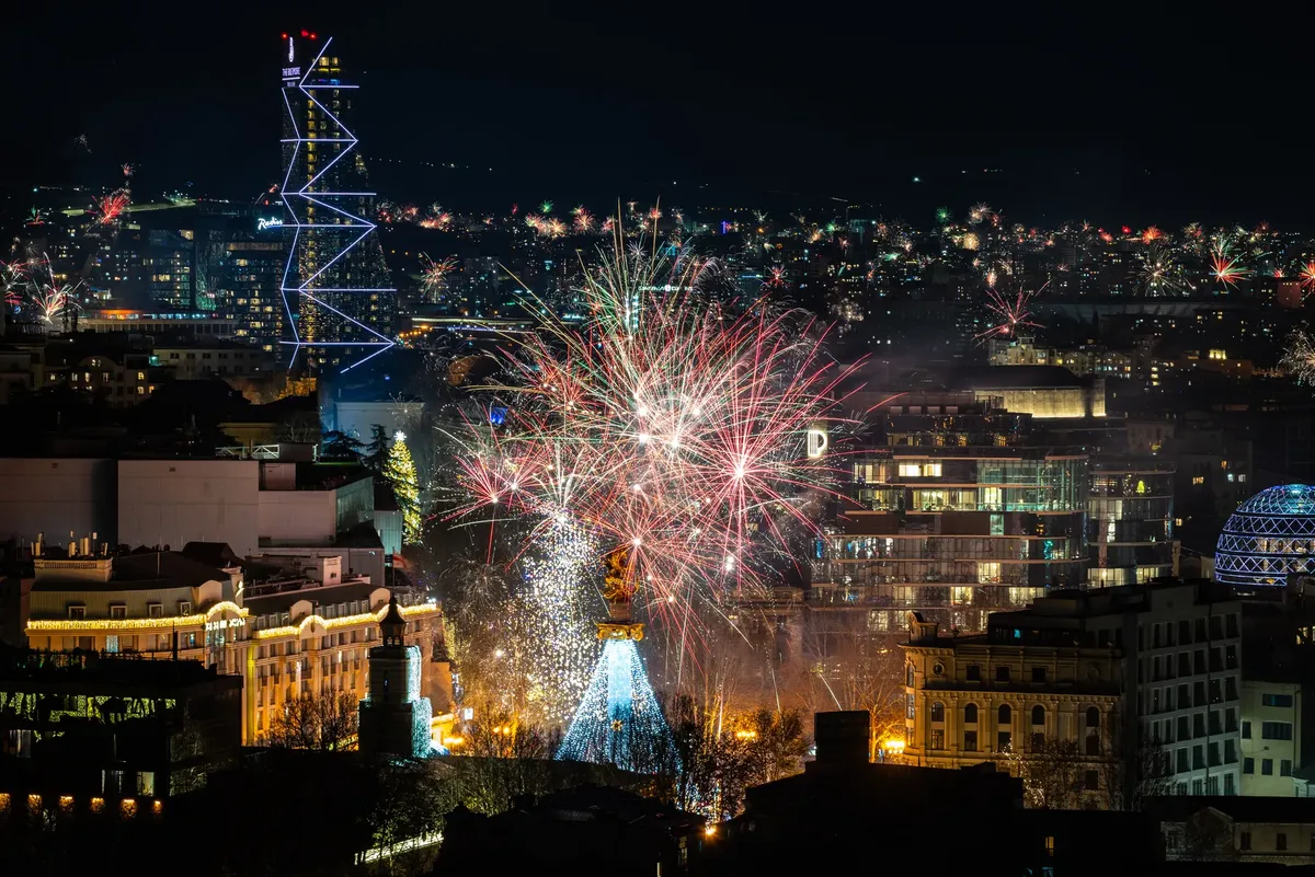 Vibrant fireworks light up the Tbilisi skyline at night, celebrating a festive occasion in Georgia.