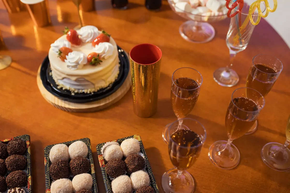 Celebrate with a delicious spread of cake, brigadeiros, and sparkling drinks on a festive table.