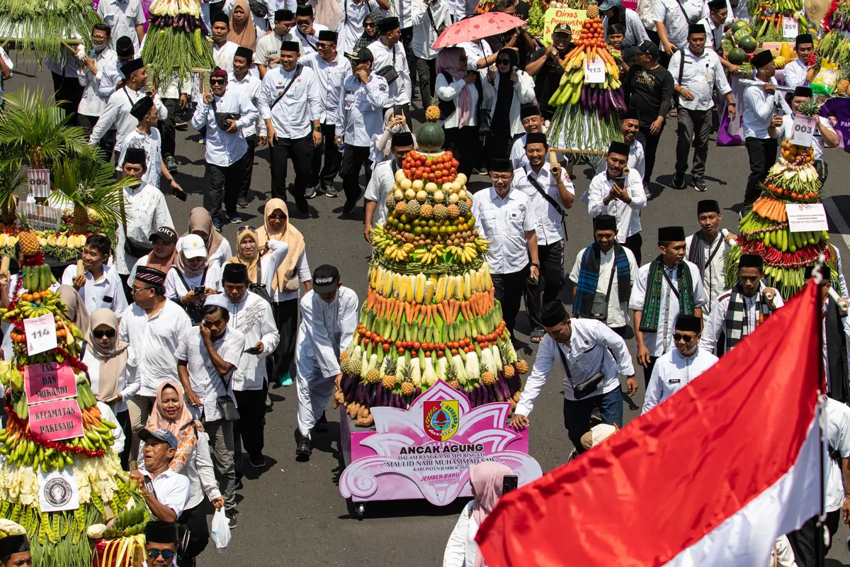 Participants parade with vibrant harvest displays during a traditional festival in Jawa Timur, Indonesia.