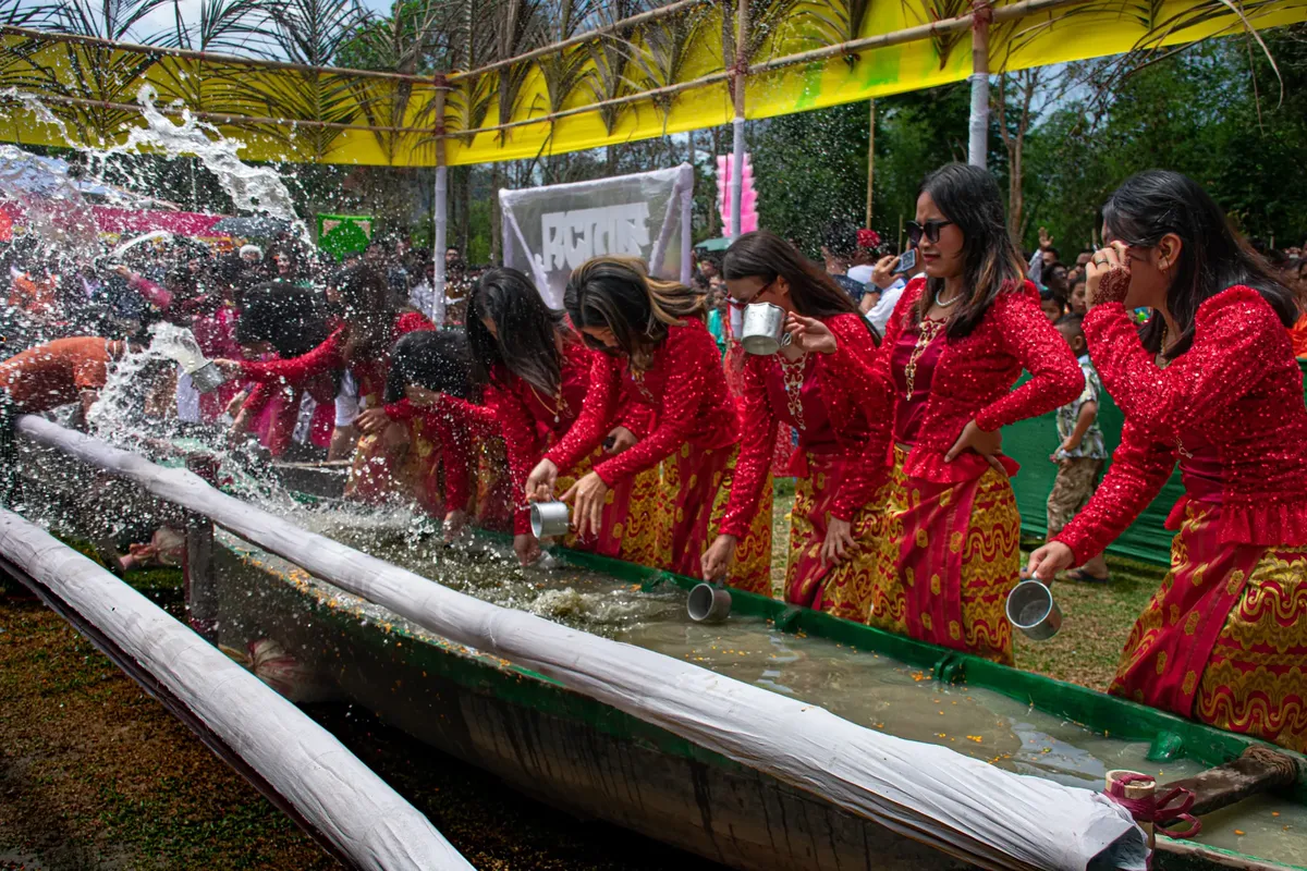 A vibrant water festival celebration with people in traditional attire participating in outdoor water activities.