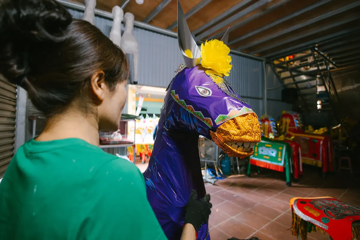 Woman in a workshop preparing a colorful, festive horse costume for a parade event.